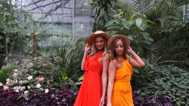 Chicas con el pelo rubio en sombreros posando en el jardín botánico — Vídeos de Stock