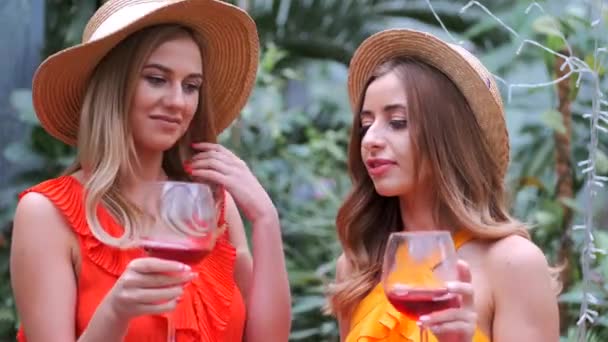 Retrato de niñas en sombreros sosteniendo copas de vino en el jardín botánico — Vídeos de Stock