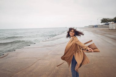 Genç kız sahilde yürüyor.