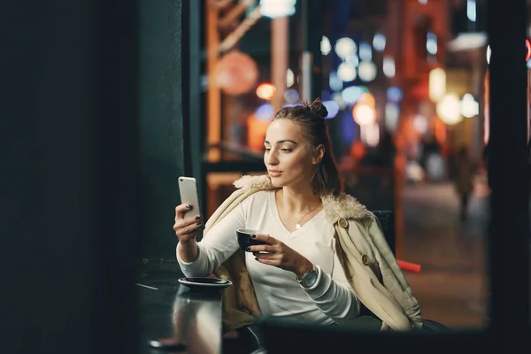Lány ül a kávézó előtt használja a telefonját — Stock Fotó