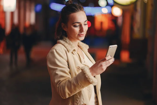 Menina verificando seu telefone fora à noite — Fotografia de Stock