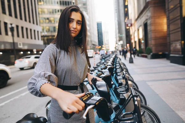 Девушка арендует городской велосипед у велостоянки — стоковое фото