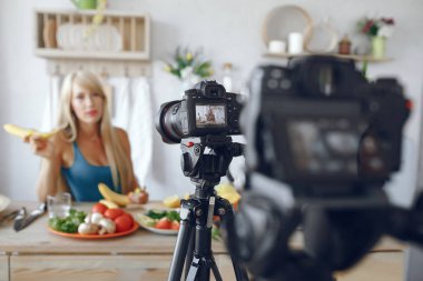 Güzel ve sportif bir kız mutfakta video kaydediyor.