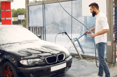 Adam arabasını yıkama istasyonunda yıkıyor.