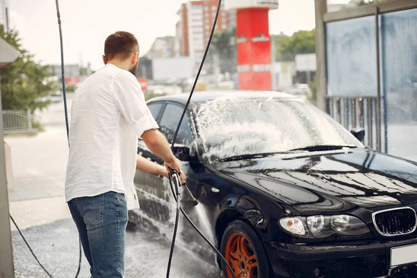 Homem bonito em uma camisa branca lavando seu carro — Fotografia de Stock