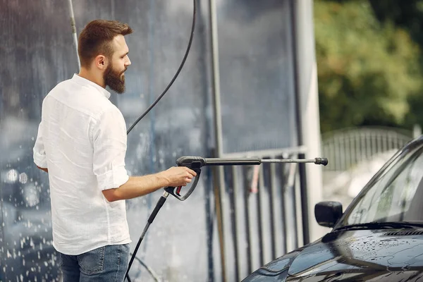 Handsomen uomo in una camicia bianca lavando la sua auto — Foto Stock