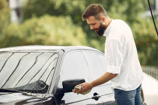 Pria berbaju putih menyeka mobil di tempat cuci mobil — Stok Foto