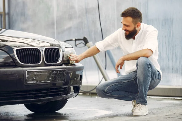 Pria berbaju putih menyeka mobil di tempat cuci mobil — Stok Foto