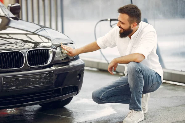 Pria berbaju putih menyeka mobil di tempat cuci mobil — Stok Foto