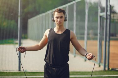 Yaz parkında ip atlayan yakışıklı bir adam.