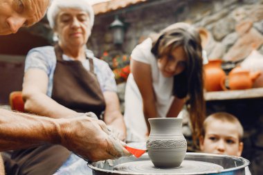 Torunları olan büyükanne çömlekçilikte sürahi yapar