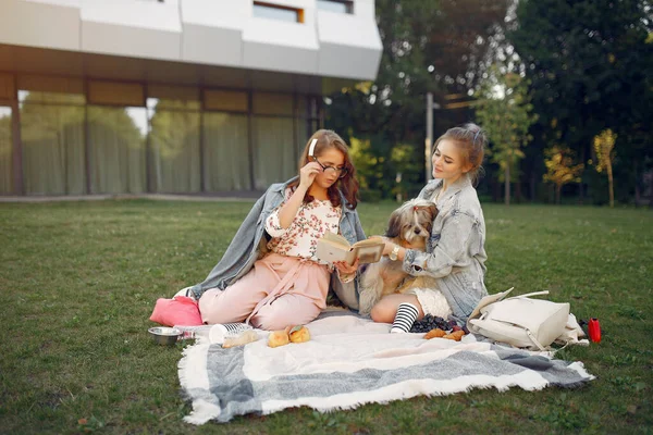 Дівчата сидять на ковдрі в літньому парку — стокове фото