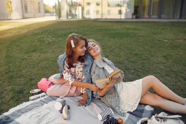 Девушки сидят на одеяле в летнем парке — стоковое фото