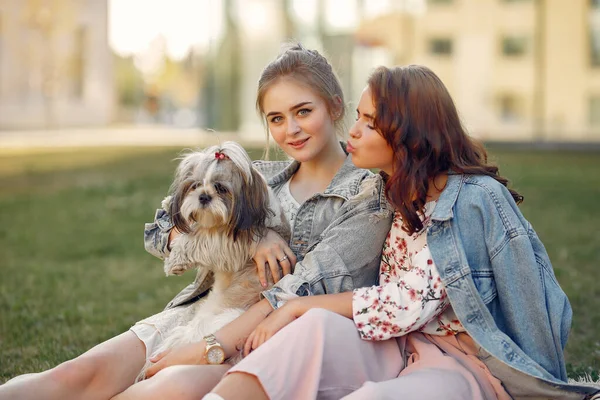 Dos chicas sentadas en un parque con un perrito — Foto de Stock