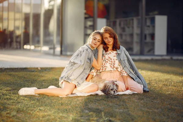 Duas meninas sentadas em um parque com um cachorrinho — Fotografia de Stock