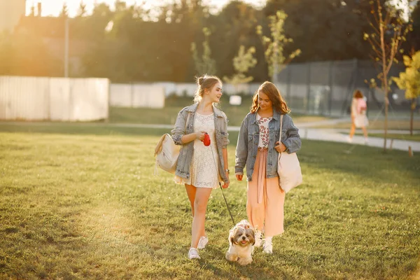 Deux filles tapissant dans un parc avec un petit chien — Photo