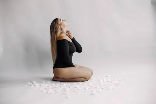 Elegant woman with blonde hair sitting in a studio — Stock Photo, Image