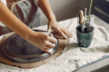 Genç bir kadın çömlekçide bulaşık yapıyor.