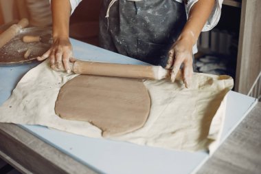 Genç bir kadın çömlekçide bulaşık yapıyor.