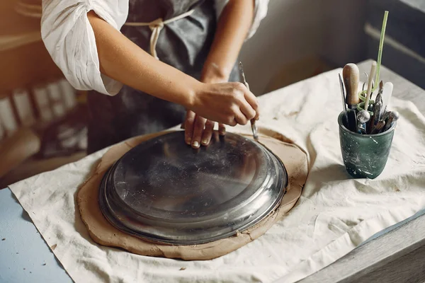 Een jonge vrouw maakt gerechten in een aardewerk — Stockfoto