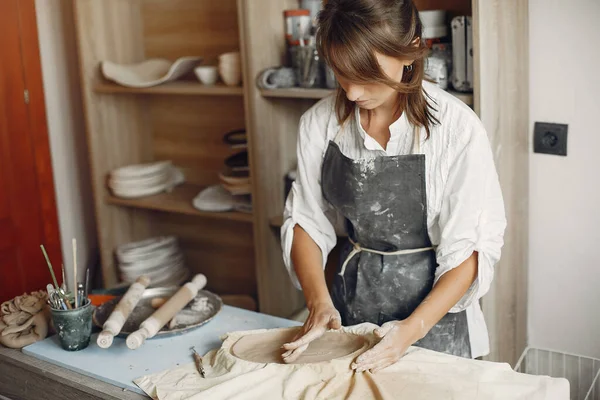 Een jonge vrouw maakt gerechten in een aardewerk — Stockfoto