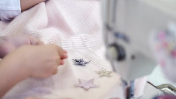 Little girl attaches star shaped stickers to fabric in garment factory — Stock Video