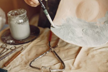 Genç bir kadın çömlekçide bulaşık yapıyor.