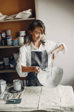 Genç bir kadın çömlekçide bulaşık yapıyor.