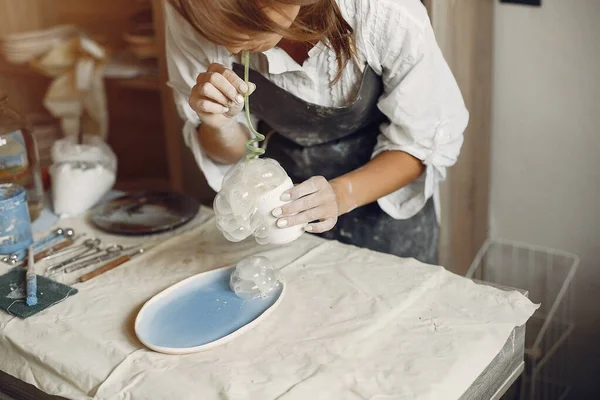 Een jonge vrouw maakt gerechten in een aardewerk — Stockfoto
