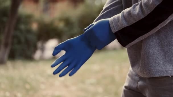 Trabajador del jardín ponerse guantes antes de comenzar su trabajo de limpieza de las hojas — Vídeo de stock