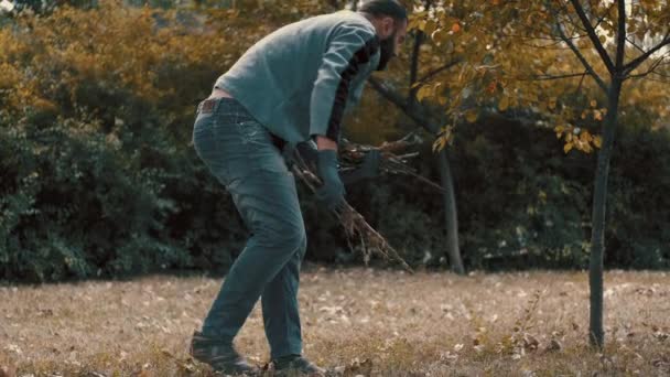 Tuinman die droge bladeren en boomtakken op een kruiwagen laadt — Stockvideo