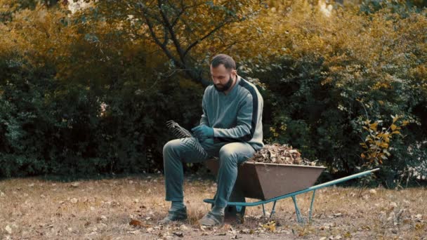 Giardino lavorato che è un uomo rimuovere e pulire le foglie secche dal rastrello — Video Stock