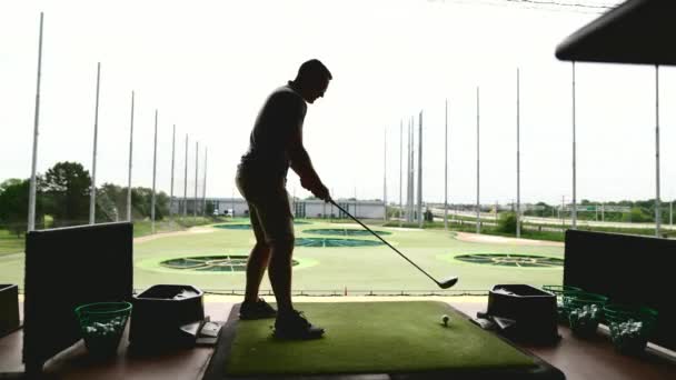 Silhuett av en man som spelar top golf på en lekplats med en pinne i händerna på en grön gräsmatta bakgrund — Stockvideo