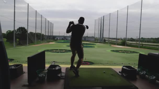 Silhuett av en man som spelar top golf på en lekplats med en pinne i händerna på en grön gräsmatta bakgrund — Stockvideo