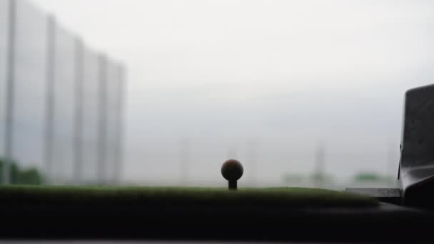 Primer plano de la pelota de golf en tee con club de golf con vistas al campo de prácticas en Topgolf — Vídeo de stock