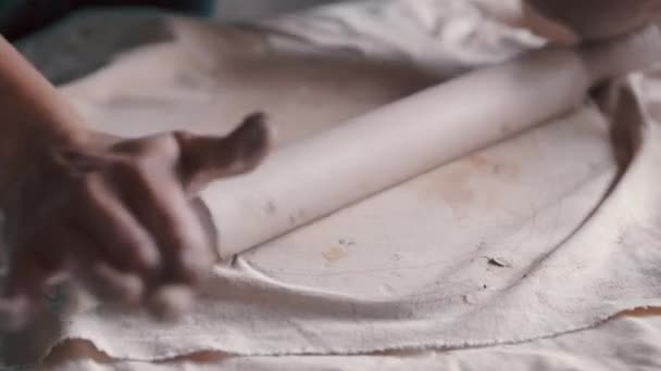 Una mujer alfarera con un delantal preparando y rodando arcilla — Vídeo de stock