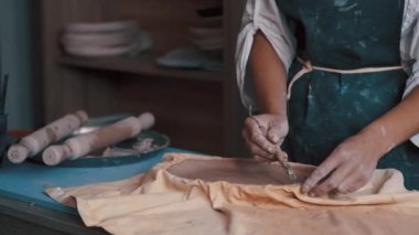 Çömlekçi mükemmel şekli elde etmek için bir şekil ve araçlar kullanarak bir çanak çömlek oluşturur.