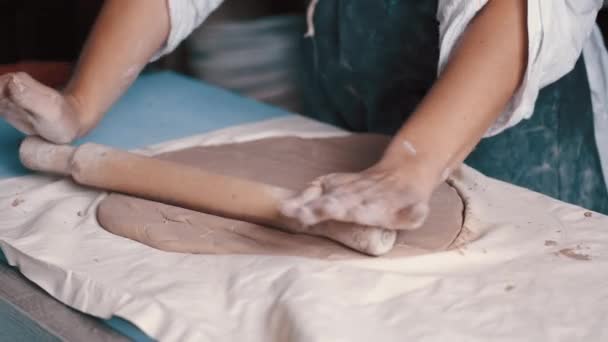 Een vrouw pottenbakker draagt een schort bereiden en rollen klei — Stockvideo