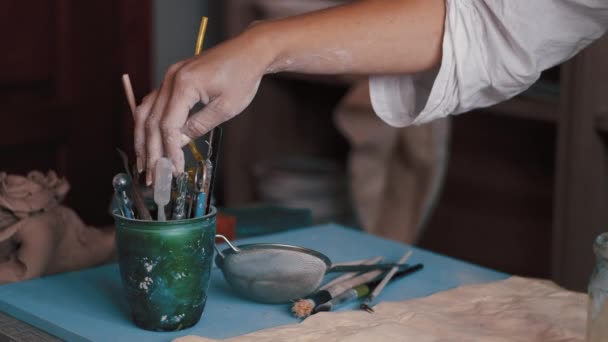 Pottenbakker kunstenaar op zoek naar het juiste gereedschap in haar atelier — Stockvideo