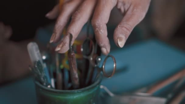 Artista alfarera en busca de la herramienta adecuada en su estudio — Vídeo de stock