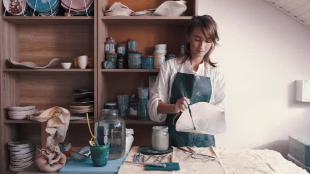 Професійний гончар прикрашає і малює тарілку після того, як вона запікає її в печі — стокове відео