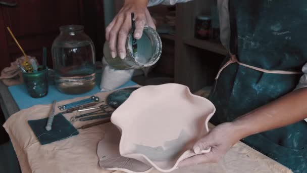 Professionell krukmakare dekorera och måla en skål efter att hon har bakat den i ugnen — Stockvideo
