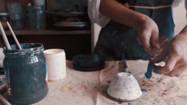 Profesyonel çömlekçi fırında pişirdikten sonra bir tabak boyuyor ve dekore ediyor.