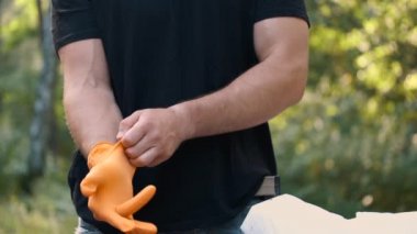 Adam parkta çöp toplamadan önce lastik eldiven takıyor.