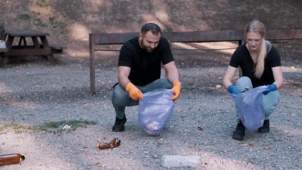 Два волонтери збирають сміття в громадському парку як вихідні — стокове відео
