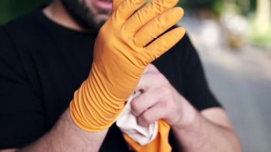 Adam yerel bir parkta gönüllü olarak çalıştıktan sonra lastik eldiven çıkarıyor.