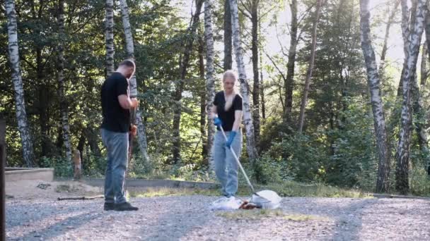 Frivilliga sopar jord och torra löv med en kvast i en lokal park — Stockvideo