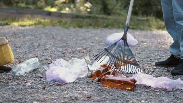 Frivilliga sopar jord och torra löv med en kvast i en lokal park — Stockvideo