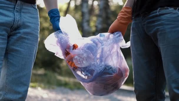 Ormanı temizledikten sonra çöpü atan ve plastik şişeleri geri dönüştüren iki gönüllü. — Stok video