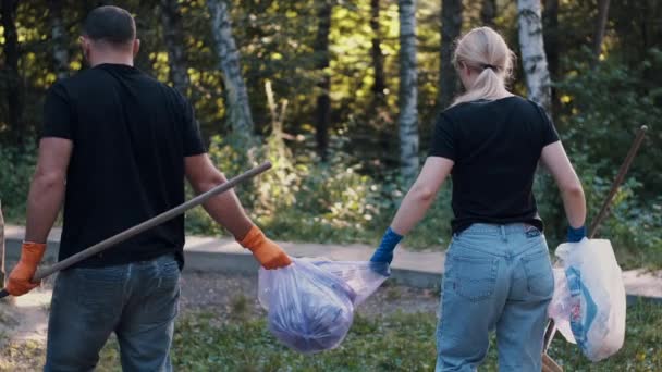 森を掃除した後二人のボランティアがゴミを出しペットボトルをリサイクルし — ストック動画